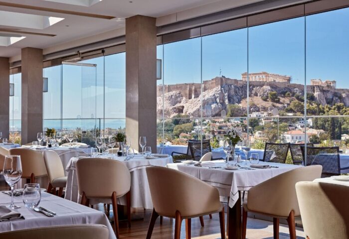 Electra Metropolis Hotel's gay-friendly restaurant boasts Acropolis views. Tables are set for fine dining with white linens and glassware.