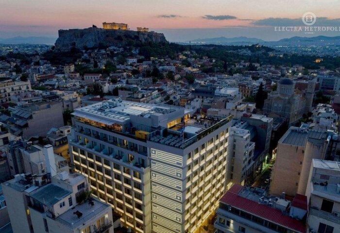 Electra Metropolis Hotel, a gay-friendly hotel in Athens. Aerial view of the hotel with the Acropolis in the background at dusk.