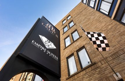 Empire Suites, a gay-friendly hotel. Exterior view of the hotel building with a checkered flag. Gay travel advice for lodging and accommodations.