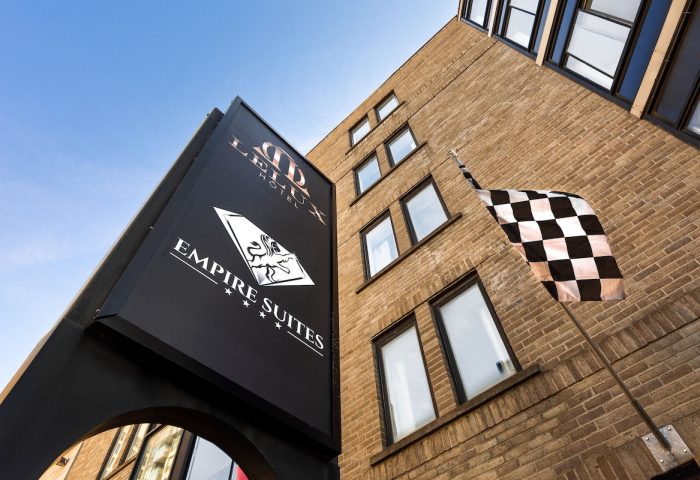 Empire Suites, a gay-friendly hotel. Exterior view of the hotel building with a checkered flag. Gay travel advice for lodging and accommodations.