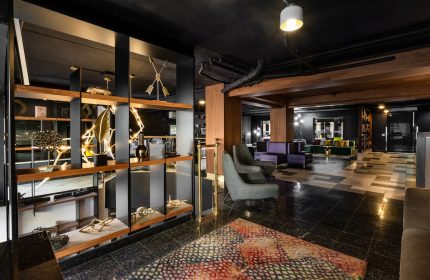 Empire Suites, a gay-friendly hotel. Lobby interior with modern decor, stylish seating, and artistic shelving. Upscale travel experience.