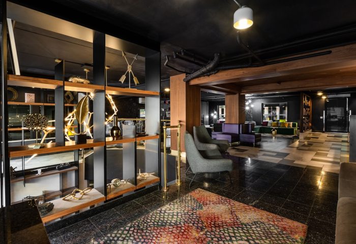 Empire Suites, a gay-friendly hotel. Lobby interior with modern decor, stylish seating, and artistic shelving. Upscale travel experience.