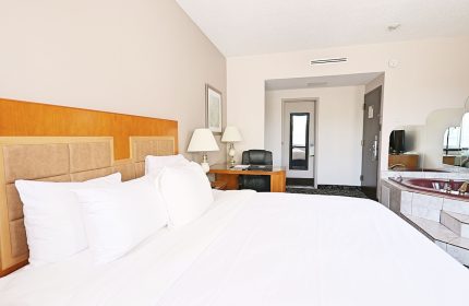 Empire Suites gay-friendly hotel room. King bed with white linens, desk, and jacuzzi tub. Comfortable stay for gay travelers.
