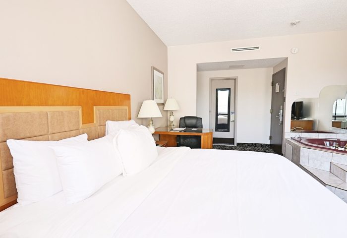 Empire Suites gay-friendly hotel room. King bed with white linens, desk, and jacuzzi tub. Comfortable stay for gay travelers.