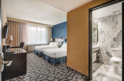 Empire Suites gay-friendly hotel room with two beds, desk, and bathroom with marble walls. Gay travel lodging.