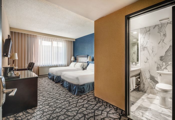 Empire Suites gay-friendly hotel room with two beds, desk, and bathroom with marble walls. Gay travel lodging.