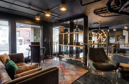 Empire Suites, a gay-friendly hotel. Modern lounge area with seating, desk, and shelving. Stylish interior design for gay travelers.