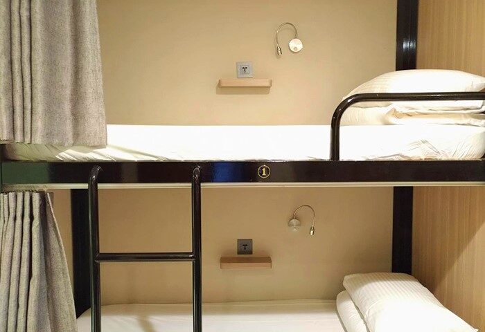 Bunk beds at Energy Inn, a gay-friendly hotel. Each bed has a curtain, light, shelf, and outlet. Ideal for budget gay travel.