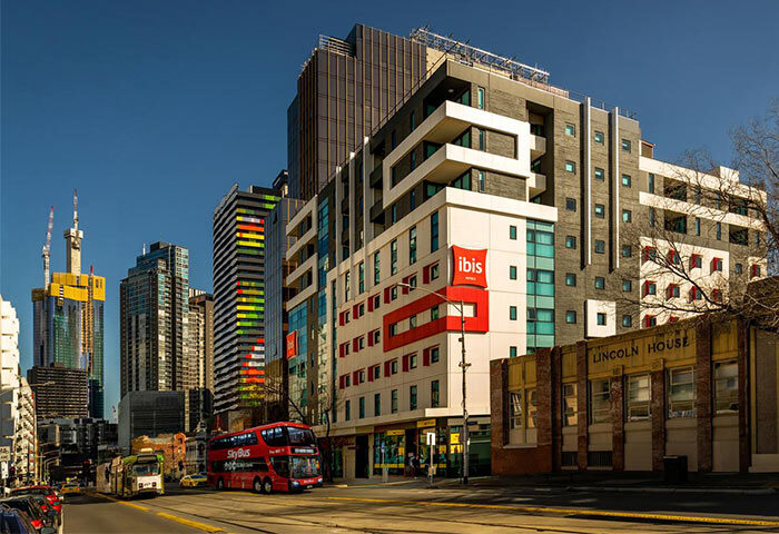 Essence Hotel Carlton: A gay-friendly hotel in Melbourne, Australia. View of the Ibis hotel with city skyline, bus and tram.