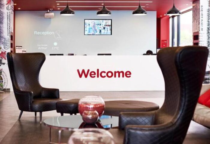 Essence Hotel Carlton lobby. Gay-friendly hotel reception area, seating, and 'Welcome' sign. Modern design for gay men's travel advice.