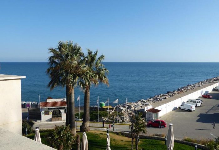 View from Estela Barcelona, a gay-friendly hotel. Features palm trees, the sea, and a parking lot. A great choice for gay travel.