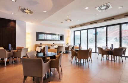 Eurostars Budapest Center gay-friendly hotel restaurant. Tables with beige chairs, black table tops, and large windows. Modern interior design.