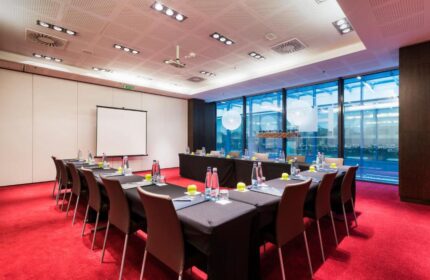 Eurostars Budapest Center gay-friendly hotel conference room. U-shaped table setup with water bottles, apples, and a projector screen.
