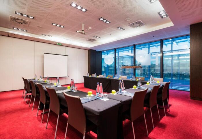 Eurostars Budapest Center gay-friendly hotel conference room. U-shaped table setup with water bottles, apples, and a projector screen.