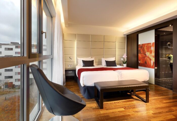 Eurostars Grand Central Hotel room. Gay-friendly hotel with double bed, modern chair, wood floors, and city view. Bathroom access.