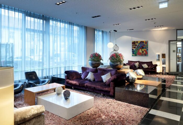 Eurostars Grand Central Hotel's stylish lobby. Gay-friendly hotel with modern design, purple sofas, and artistic decor for a welcoming atmosphere.