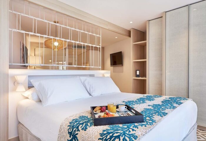 Eurostars Ibiza gay-friendly hotel room. Breakfast in bed at this stylish Ibiza hotel. Modern design with coral accents. Perfect for gay travel.