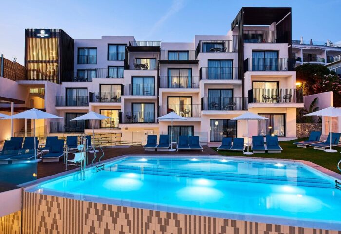 Eurostars Ibiza gay-friendly hotel pool view. Modern architecture, balconies, sun loungers, and parasols. Ideal for gay men's travel in Ibiza.
