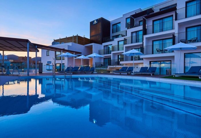 Eurostars Ibiza, a gay-friendly hotel. Pool view with lounge chairs, umbrellas, and modern architecture. Perfect for gay travel and Ibiza holidays.