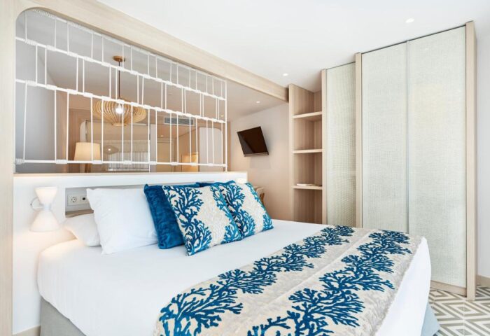 Eurostars Ibiza gay-friendly hotel room. Modern design with blue coral pattern on bed runner and pillows. Closet and TV. Relaxing vibe.