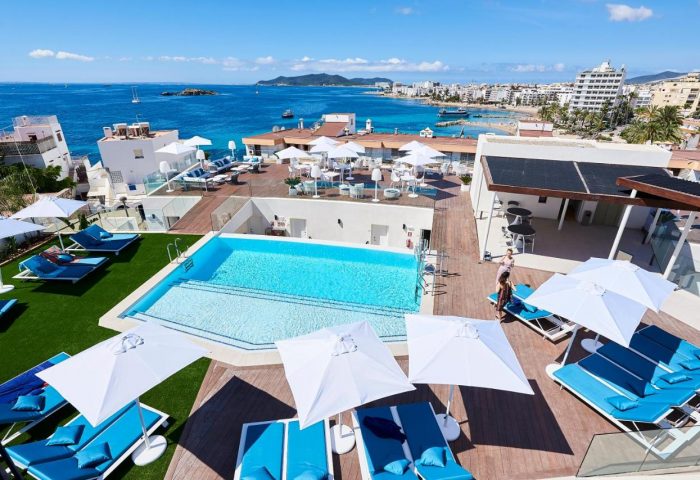 Eurostars Ibiza: Gay-friendly hotel rooftop pool view. Turquoise water, sun loungers, umbrellas. Ideal for gay travel in Ibiza, Spain.