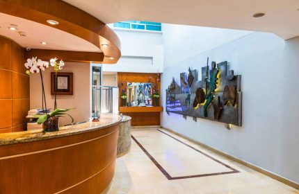 Eurostars Zona Rosa Suites lobby. Gay-friendly hotel with modern design, a reception desk with orchids, and an artistic wall feature. LGBT travel.