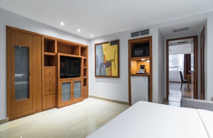 Eurostars Zona Rosa Suites gay-friendly hotel room. Wood cabinets, TV, microwave, mini-fridge, and bed. Modern suite interior.