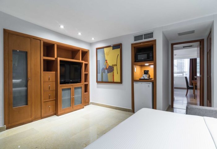 Eurostars Zona Rosa Suites gay-friendly hotel room. Wood cabinets, TV, microwave, mini-fridge, and bed. Modern suite interior.