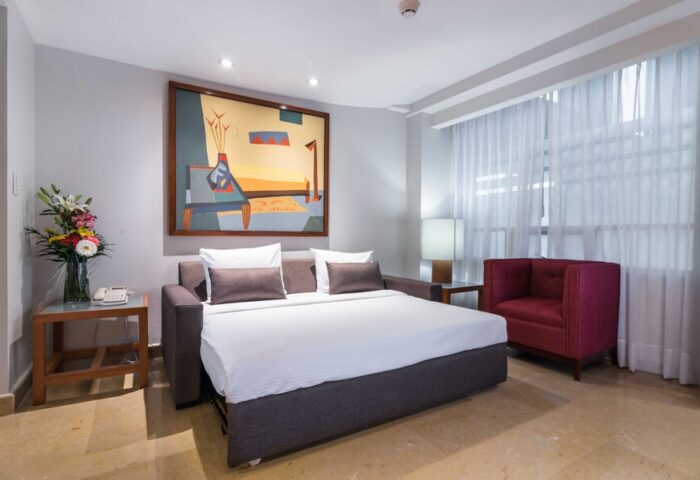 Eurostars Zona Rosa Suites gay-friendly hotel room. Pull-out bed, red chair, and modern art. Perfect for gay travelers in Mexico City.