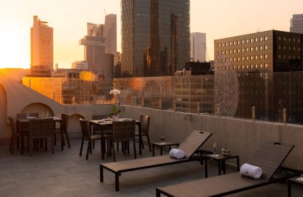 Rooftop view at Gay-Friendly Hotel Eurostars Zona Rosa Suites. Lounge chairs & dining tables overlook Mexico City's skyline at sunset. Perfect for gay travel.