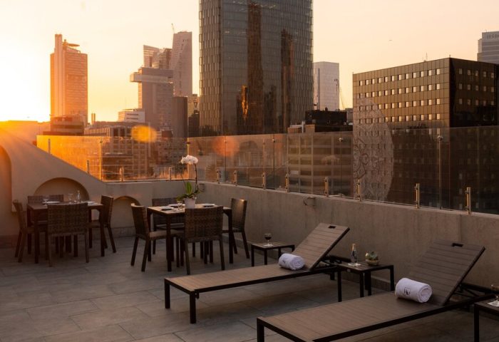 Rooftop view at Gay-Friendly Hotel Eurostars Zona Rosa Suites. Lounge chairs & dining tables overlook Mexico City's skyline at sunset. Perfect for gay travel.