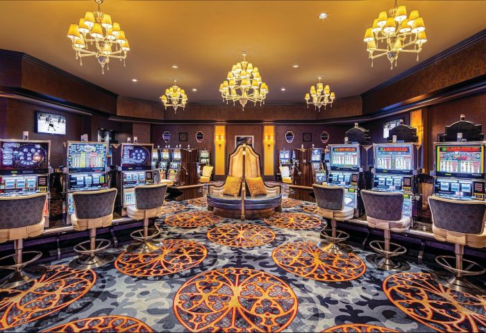 Excalibur Hotel's casino area. Slot machines line the walls, and chandeliers hang from the ceiling. Gay-friendly hotel with luxury decor.