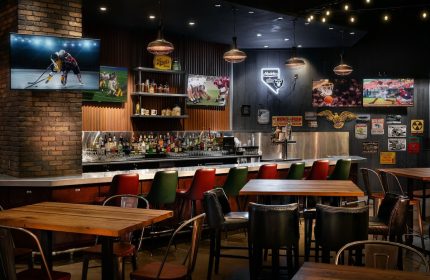 Bar area at the gay-friendly Excalibur Hotel, Las Vegas. TVs showing sports, bar stools, and tables. Great spot for gay men to hang out.