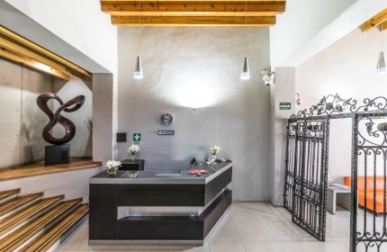 Exe Cities Reforma gay-friendly hotel lobby in Mexico City. Reception desk, iron gate, and modern decor. Stylish, welcoming space for LGBT travelers.