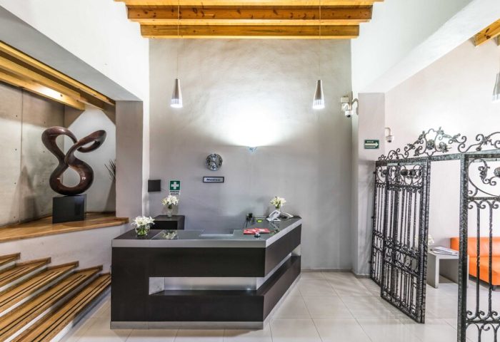 Exe Cities Reforma gay-friendly hotel lobby in Mexico City. Reception desk, iron gate, and modern decor. Stylish, welcoming space for LGBT travelers.