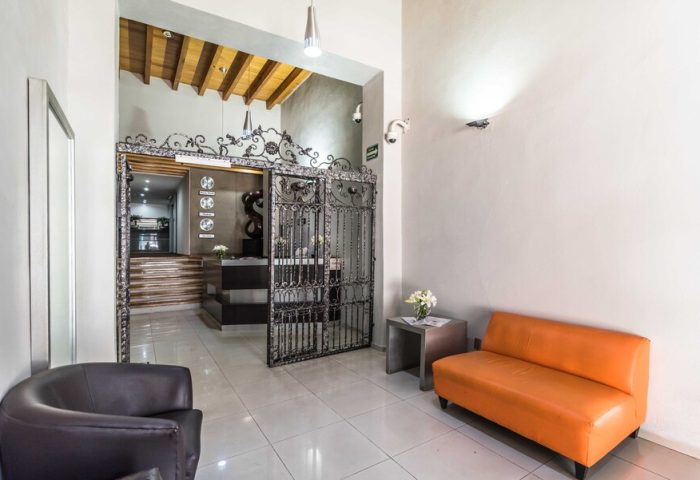 Exe Cities Reforma, a gay-friendly hotel. Hotel lobby with wrought iron gate, reception desk, and seating area. Modern design in Mexico City.