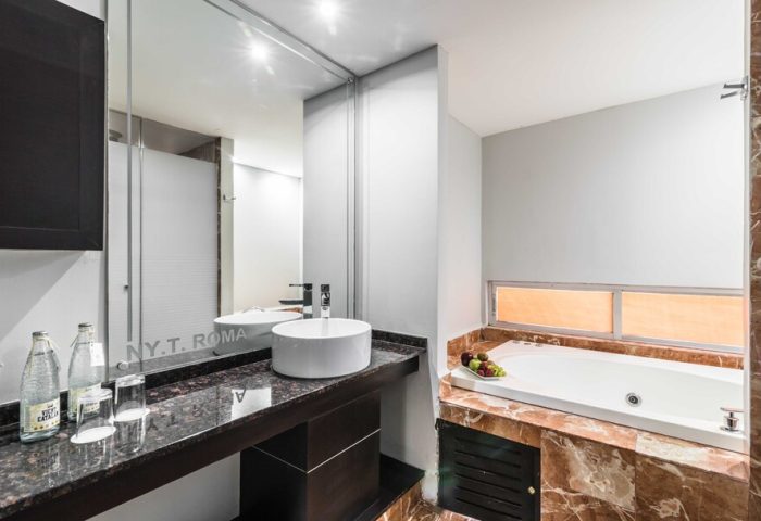 Exe Cities Reforma gay-friendly hotel bathroom. Features a modern sink, large mirror, and a luxurious bathtub with marble accents. Ideal for gay travel.