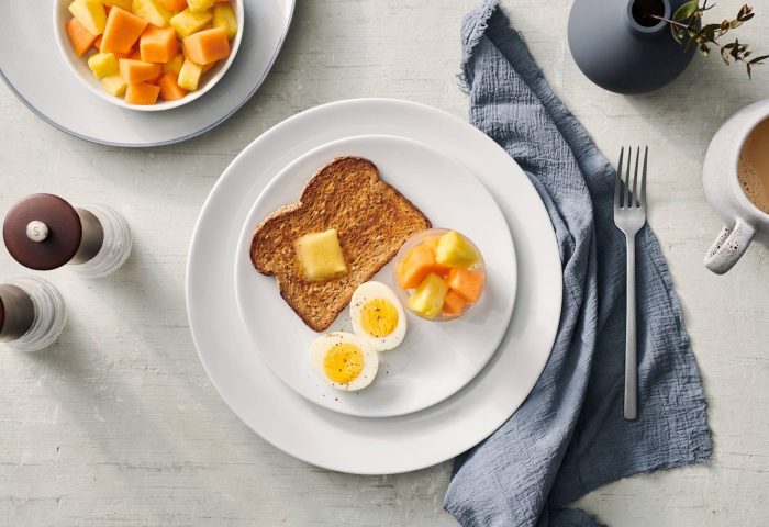 Breakfast at Fairfield by Marriott Montreal Downtown, a gay-friendly hotel. Toast, eggs, fruit, and coffee on a table setting.