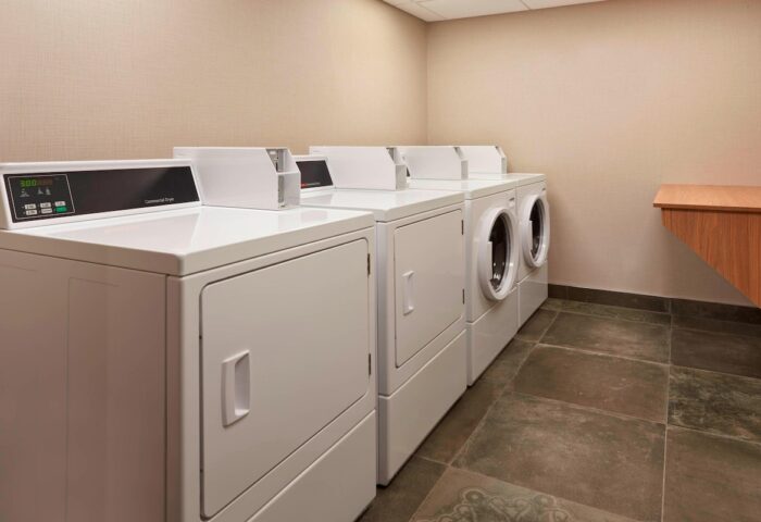 Laundry room at Fairfield by Marriott Montreal Downtown, a gay-friendly hotel. Row of commercial dryers for guests' convenience.