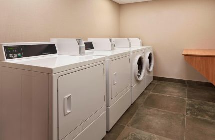 Laundry room at Fairfield by Marriott Montreal Downtown, a gay-friendly hotel. Row of commercial dryers for guests' convenience.