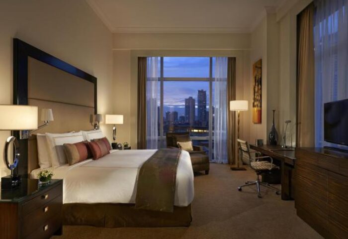 Fairmont Makati hotel room. Gay-friendly hotel with skyline view. Comfortable bed, desk, and city lights. Luxury travel in Makati, Philippines.