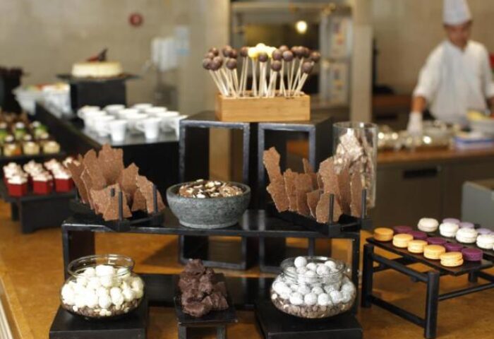 Dessert bar at Fairmont Makati, a gay-friendly hotel. Features chocolate lollipops, macarons, chocolate bark, and other sweet treats. Chef in background.