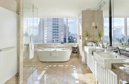 Fairmont Makati gay-friendly hotel bathroom. Bathtub with city view. Luxury hotel bathroom with double sinks, glass shower, and marble floor.