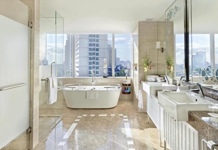 Fairmont Makati gay-friendly hotel bathroom. Bathtub with city view. Luxury hotel bathroom with double sinks, glass shower, and marble floor.