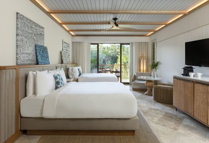 Fairmont Mayakoba's gay-friendly hotel room with two beds, balcony, modern decor, and view. A luxury travel destination for gay men.