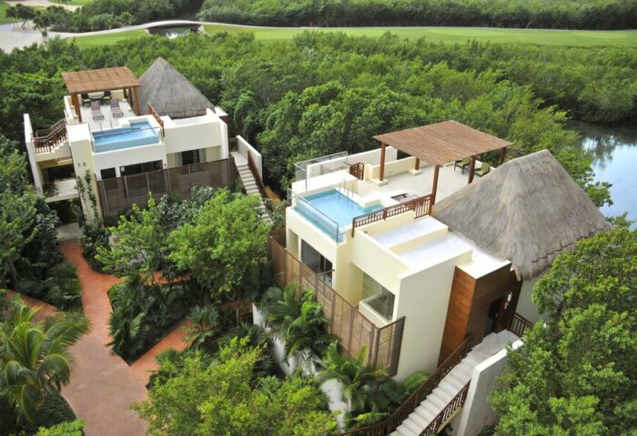 Fairmont Mayakoba gay-friendly hotel view. Luxurious suites with rooftop pools, thatched roofs, and lush greenery. Ideal for gay travel.