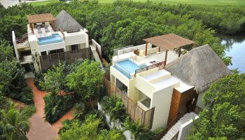Fairmont Mayakoba gay-friendly hotel view. Luxurious suites with rooftop pools, thatched roofs, and lush greenery. Ideal for gay travel.