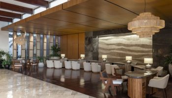 Fairmont Mayakoba, a gay-friendly hotel. Lobby with modern lighting, wood accents, and seating. A stylish choice for gay travelers.