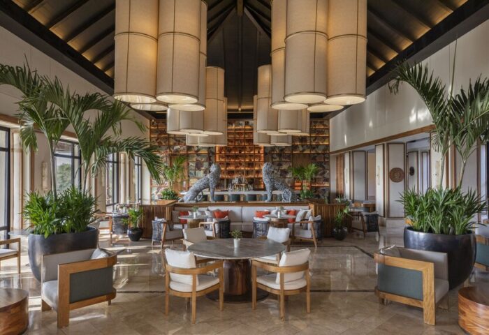 Fairmont Mayakoba's gay-friendly hotel interior. Lobby lounge with seating, bar, plants, and unique lighting. A luxury travel option for gay men.