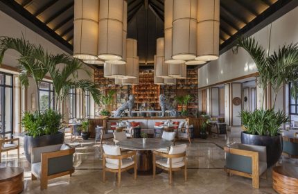 Fairmont Mayakoba's gay-friendly hotel interior. Lobby lounge with seating, bar, plants, and unique lighting. A luxury travel option for gay men.